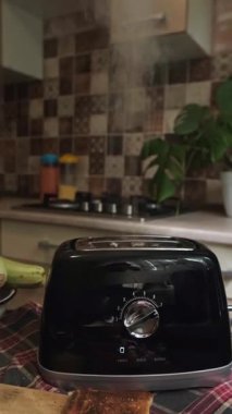 Kızarmış ekmek, tost makinesinden yükselen buhar ve hafif dumandır ve sabah sıcacık bir mutfak atmosferi yaratır. Yüksek kalite 4k görüntü