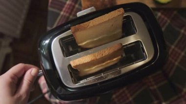 Kız ekmek kızartma makinesini açıyor ekmek dilimlerini aşağı bastırıyor mutfak sahnesinden yavaşça aşağı. Yüksek kalite 4k görüntü