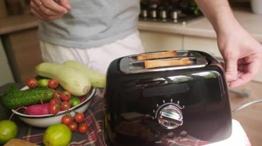 Avokado tostu hazırlamak için ekmek kızartan sağlıklı yaşam tarzı adamı güne basit ev yapımı yemekle başlıyor. Yüksek kalite 4k görüntü