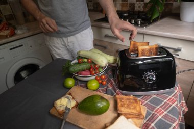 Adam tost makinesini kullanarak sebze ve avokadoyla tost hazırlıyor.