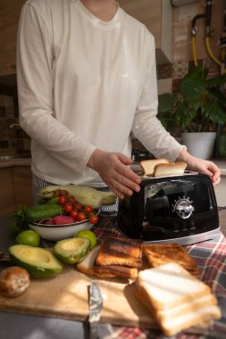 Kadın sabah avokado tostu ve sebze hazırlıyor. Evde sağlıklı bir başlangıç için kolay ve lezzetli bir kahvaltı.