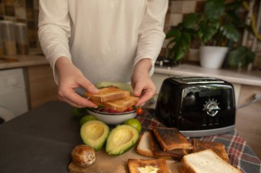 Mutfakta bir kadın, sabah tost makinesiyle evde sağlıklı yiyecekler hazırlıyor besleyici kahvaltı için basit bir rutin..