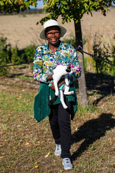 stock image Smiling African woman with a pet cat. Portrait in exterior with the sky as a background. Pet therapy against loneliness and depression concept