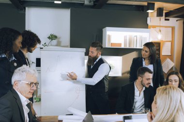 Yönetici iş planlarını meslektaşlarına ve çalışanlarına gösteriyor. Ticari strateji çizimi ve planlaması olan ilan panosu. İş toplantısı ve sonuçlar tartışması