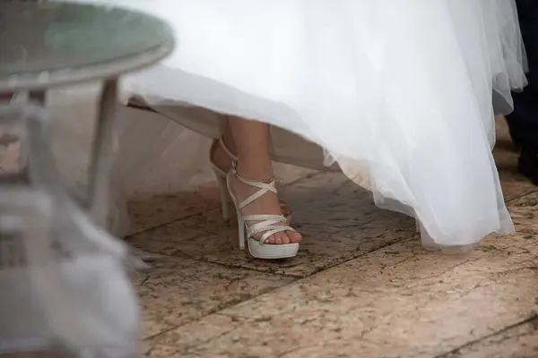 the bride\'s stylish white high heels complement the graceful flow of her wedding gown\'s fabric