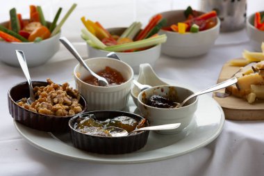 Beyaz tabakta küçük kaseler dolusu reçel, jöle ve ceviz var. Lezzetli lezzetler sunuyor.