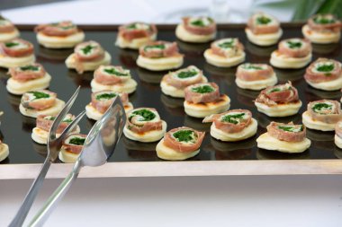 Küçük rulo prosciutto aperatifleri bir etkinlik için siyah servis tepsisine konur.