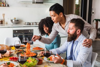 Bir grup arkadaş bir masada oturup makarna ve şarabın tadını çıkarıyorlar.