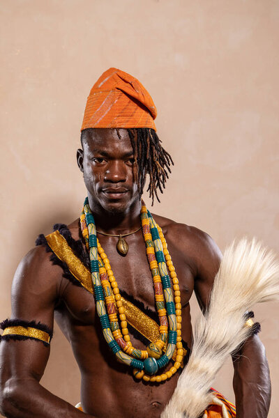 Африканская танцовщица позирует в традиционной одежде, ювелирных украшениях и веере перьев