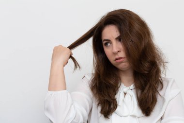 Genç iş kadını yüzünde endişeli bir ifadeyle saçını çekiyor.