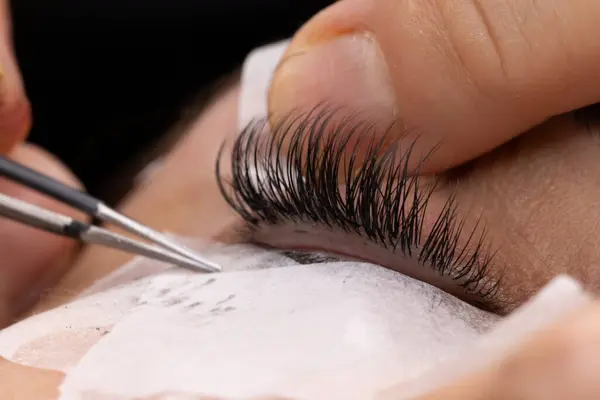 stock image Beautician is applying individual false eyelashes to a client's eye for a more dramatic and glamorous look