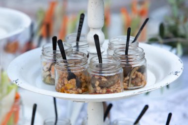 Aperatiflerle dolu cam kavanozlar ve küçük kaşıklar konukların ziyafet için gelmesini bekliyor.