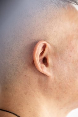 Kısa saçlı, kulağına odaklanmış bir adamın kafasının kenarına yakın çekim.