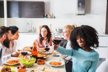 Mutlu çoklu etnik arkadaşlar birlikte yemek yiyor, dostluğu kutluyor ve güzel anları paylaşıyorlar.