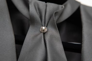 Elmas broşlu gri bir kravat, erkek modası ve aksesuarları sergileniyor.