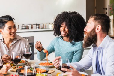 Bir grup çok ırklı genç arkadaş evde makarna ve kırmızı şarap eşliğinde arkadaşlığımızı ve beraberliğimizi kutluyoruz.