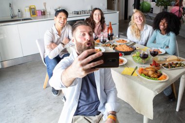 Neşeli arkadaşlar evde öğle yemeği yerken selfie çekiyorlar.
