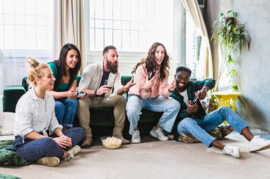 Mutlu arkadaşlar eğleniyor, şarap içiyor ve video oyunu oynarken patlamış mısır yiyor.