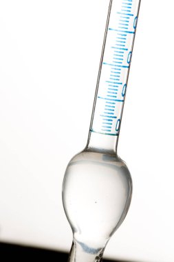 Mavi ölçekli cam hacim pipeti, hassas ölçümler için kullanılan şeffaf sıvıyı içerir ve laboratuvarda belirli miktarda sıvı transferi yapılır.