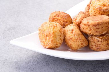 Taze pişmiş altın sarısı gougres, lezzetli peynirli börekler, beyaz bir tabağa dizilmiş, tadını çıkarmaya hazır..