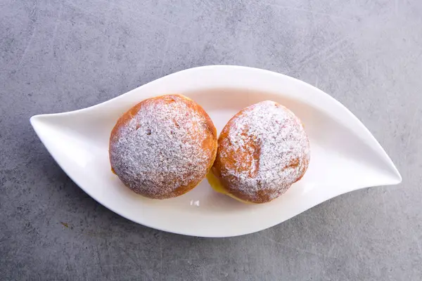 Krema şekerli iki lezzetli ev yapımı donut beyaz bir tabakta servis edilir.