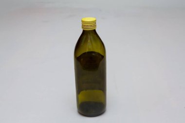 Beyaz arka planda duran sarı şapkalı boş yeşil cam şişe.