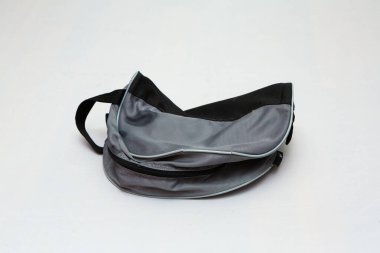 Küçük gri ve siyah tuvalet çantasının sapı hafif kıvrımlı ve beyaz arka planda duruyor.