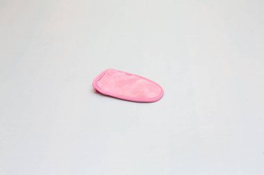 Düz beyaz arka planda yumuşak pembe deri yüzme eldiveni, cilt bakımını ve güzellik alışkanlıklarını teşvik eder.