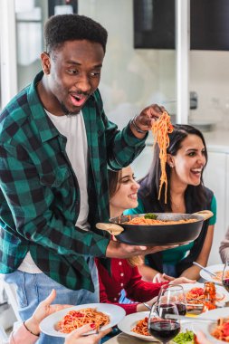 Mutlu bir adam yemek saatinde arkadaşlarına domates soslu lezzetli bir spagetti servis ediyor.