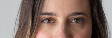 Kahverengi gözlü, özgüven, güç ve kararlılık gösteren bir kadının portresi.