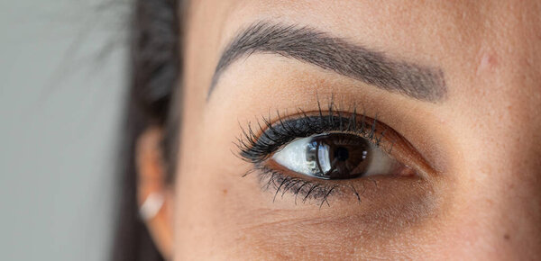 Крупный план женского глаза, подчеркивающий ее длинные ресницы и брови идеальной формы
