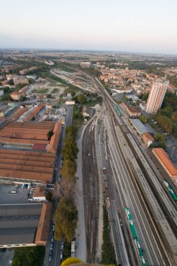 Gün batımında şehir manzarası boyunca uzanan demiryolu raylarının havadan görünüşü