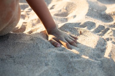 Çocuk yaz tatilinde kumsalda kumla oynuyor.