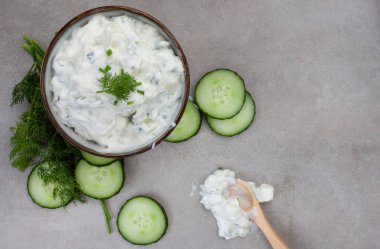 Taze Yunan yemeği, salatalık, yoğurt ve ottan yapılmış Tzatziki. Benekli gri bir yüzeyde kopyalama alanı