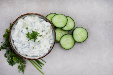 Fresh Greek favorite, Tzatziki made with cucumber, yogurt and herbs. On a mottled grey surface with copy space clipart
