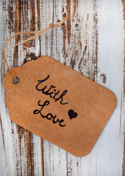cardboard gift tag, written with love on a rustic wooden background