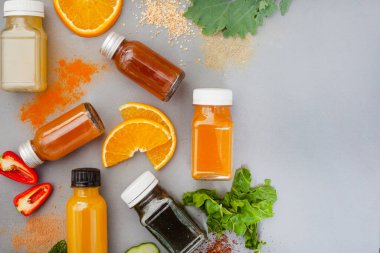 Juice shots for a healthy lifestyle, flat lay on dark grey with ingredients and copy space on right