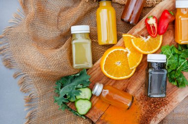 Juice shots for a healthy lifestyle, flat lay on rustic surface with ingredients and copy space on the right