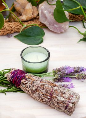 Smudge stick with candle and lavender on a table with plants and crystals