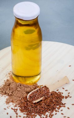 scoops of flax seeds, flax seed powder and flax seed oil on light wood