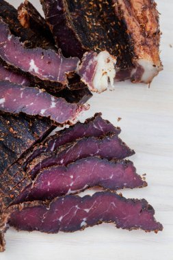 Freshly cut South African biltong on light wooden surface