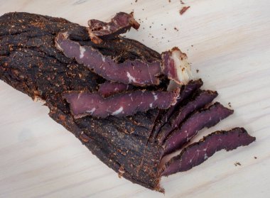 Freshly cut South African biltong on light wooden surface
