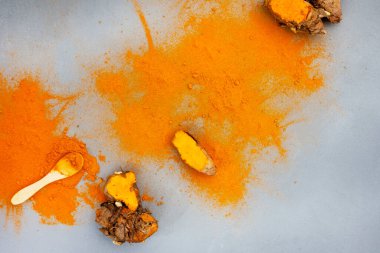 Turmeric rhizomes and powder flat lay on grey with copy space