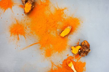 Turmeric rhizomes and powder flat lay on grey with copy space