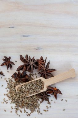Aniseed and pods on light wooden surface with wooden scoop