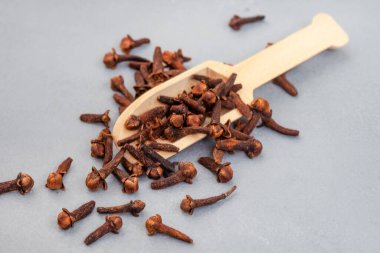 flat lay with scoop of whole cloves on mottled gray with copy space