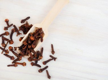 flat lay with scoop of whole cloves on light wood with copy space