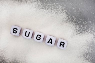 Sugar written in letter dice on white sugar granules
