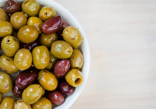 Mixed marinated olives on light wooden surface with copy space
