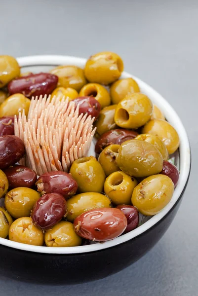 Mixed marinated olives in cocktail bowl on gray